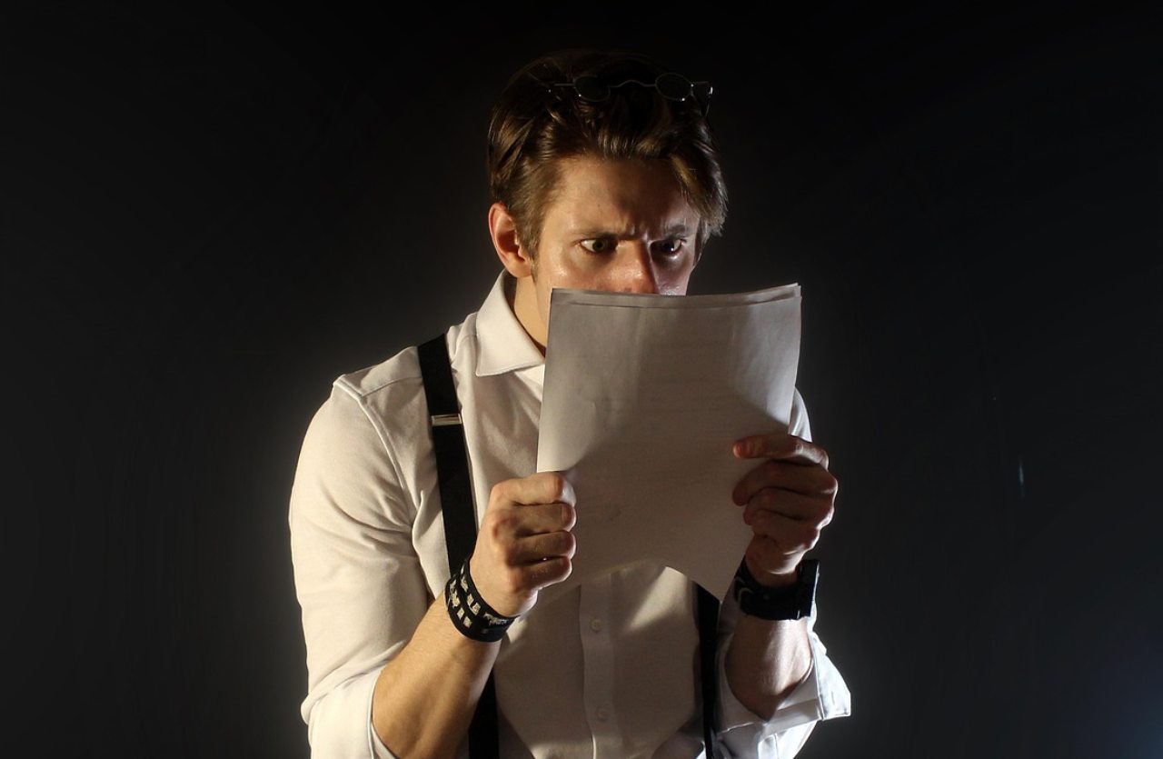 uomo che legge un documento su sfondo nero