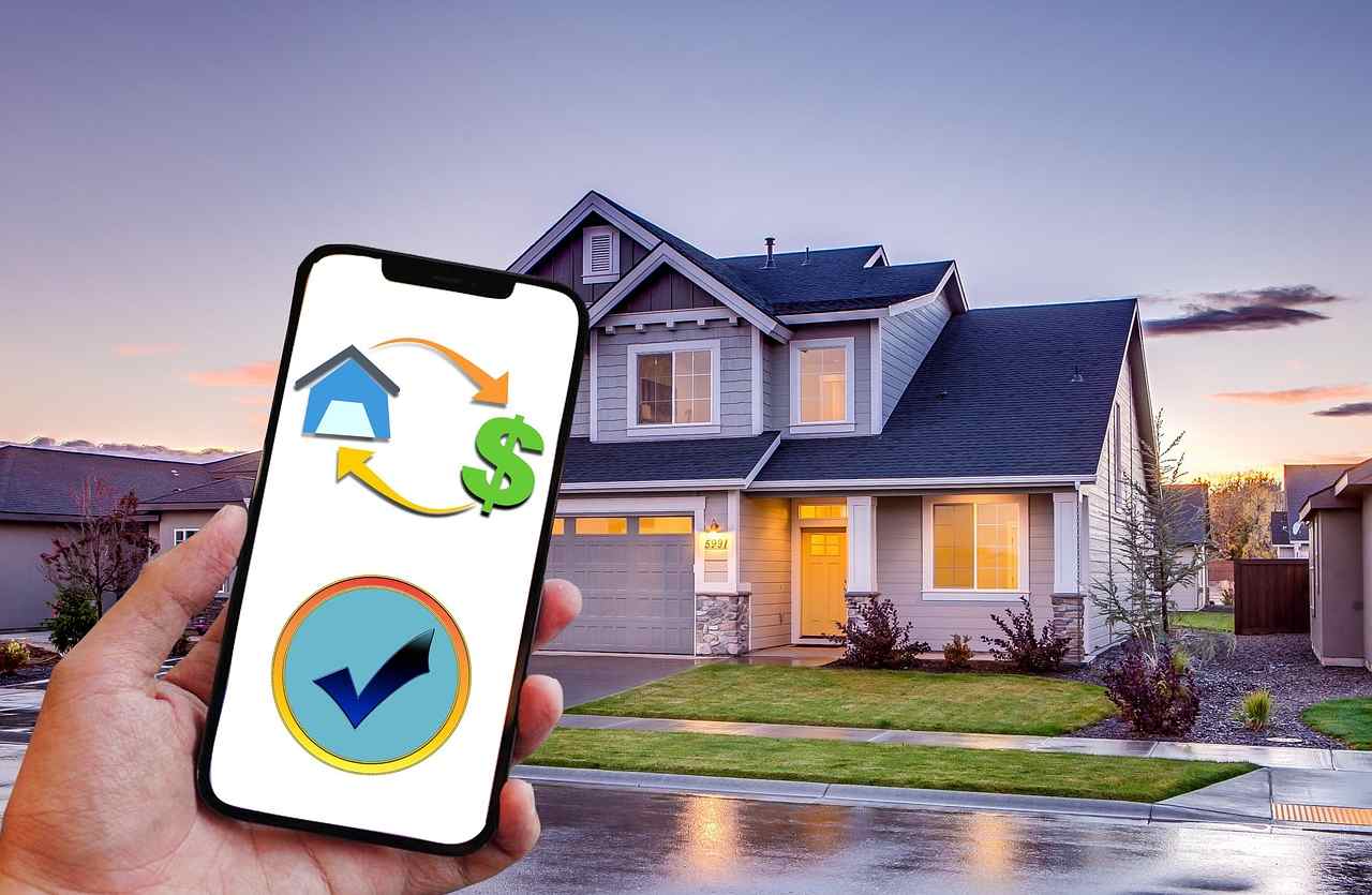 mano con cellulare e casa sullo sfondo